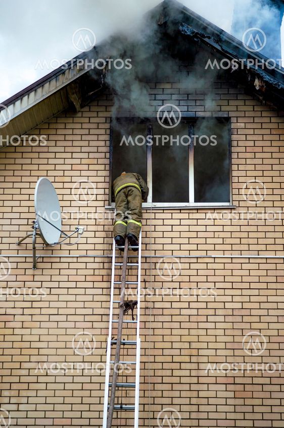 A firefighter puts out a burning building with height...