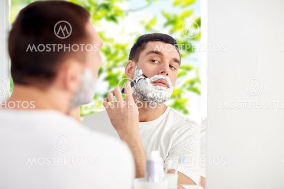 man shaving beard with razor blade at bathroom