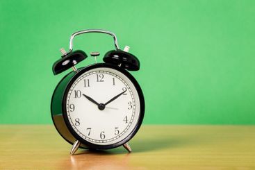 Black vintage alarm clock on wooden table