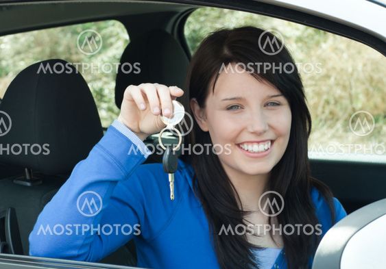 Radiant teenager holding car keys sitting in her new car