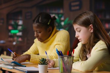 Caucasian tutor guiding elementary school girl at a...