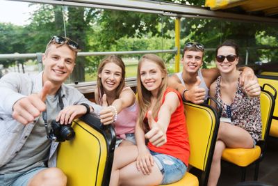 friends traveling by tour bus showing thumbs up