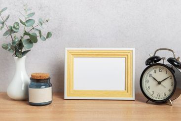 Empty photo frame, alarm clock, eucalyptus branches and...