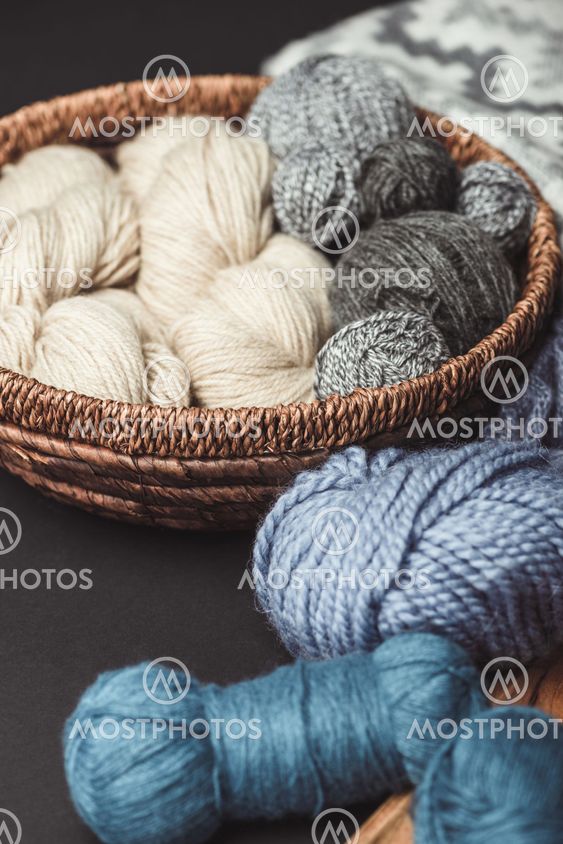 close up view of knitting clews in wicker basket on dark...