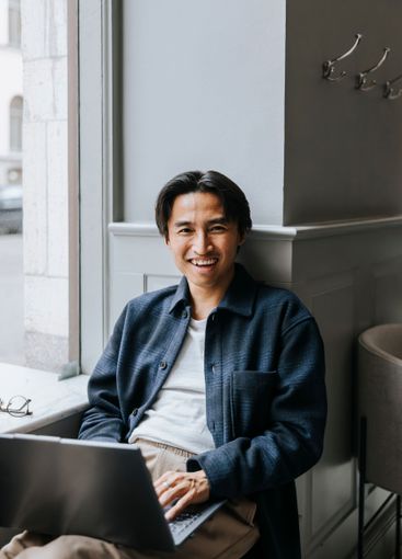 Portrait of happy male business professional sitting with...