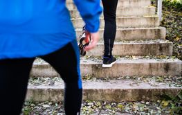 Unrecognizable athletes running on stairs on sunny autumn day.