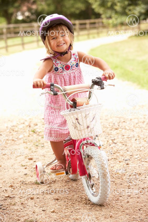 Girl Learning To Ride Bike Wearing Safety Helmet