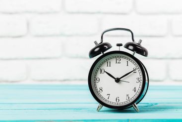 Black vintage alarm clock on wooden table