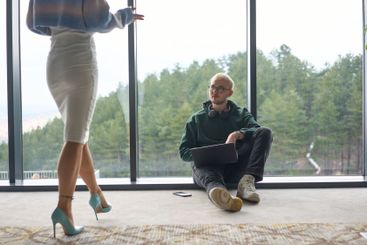 A blonde man sitting casually on the floor of a modern...
