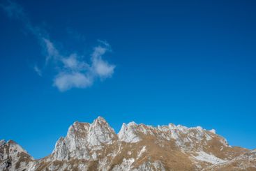 Rocky mountain peaks touching blue sky with cloudscape...