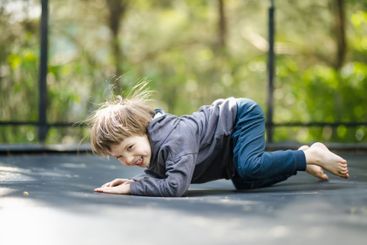 Little boy jumping on a trampoline in a backyard on warm...