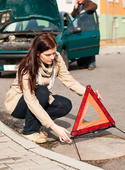 Woman putting triangle sign for car breakdown