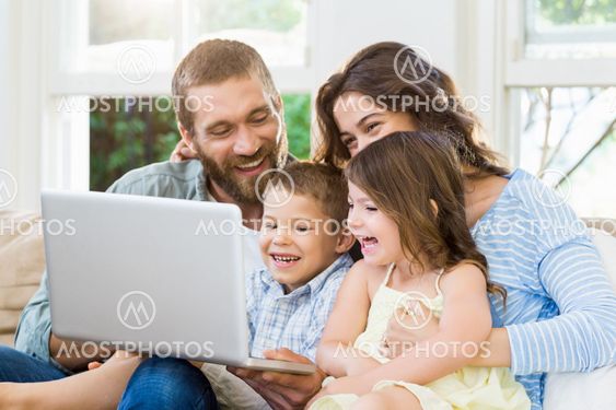 Parents and kids using laptop in living room