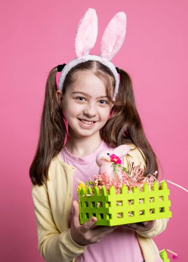 Young smiling kid showing decorated basket with eggs and...