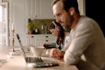 Teenage girl using digital tablet near father working at...