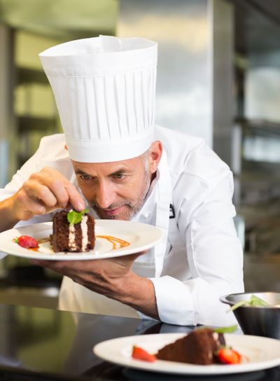 Concentrated male pastry chef decorating dessert in kitchen