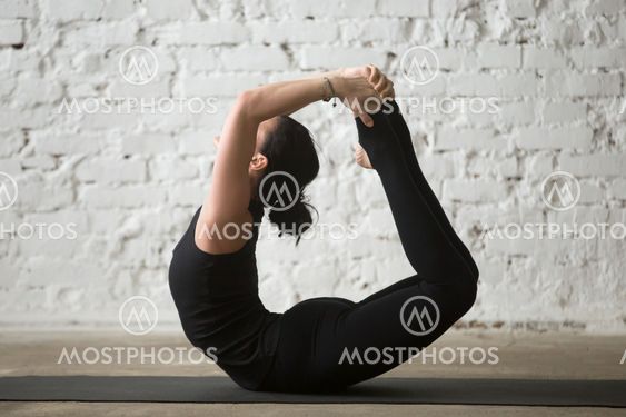 Young yogi attractive woman in Bow pose, white loft background