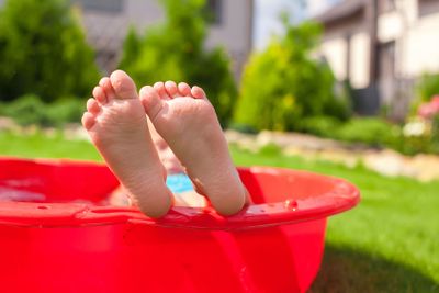 Closeup of little kid's legs in small red pool