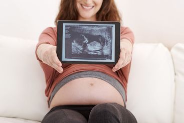 Home, woman and happy with pregnancy scan on sofa in...