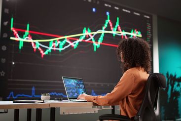 Female Stock Analyst Analyzing Data on Computer Screens