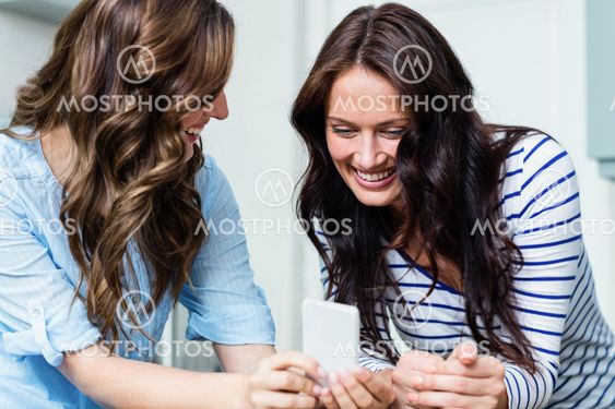 Smiling female friends using mobile phone