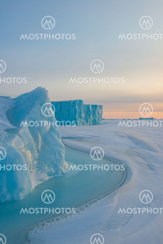 Ice berg on frozen sea at sunrise