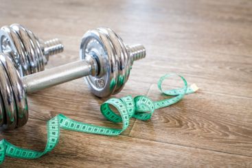 Fitness concept with dumbbells and measuring tape