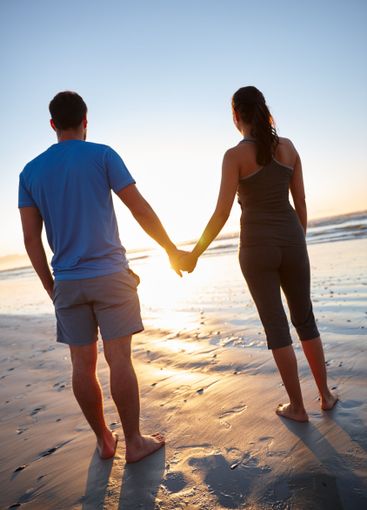 Love, holding hands and sunset with couple at beach for...