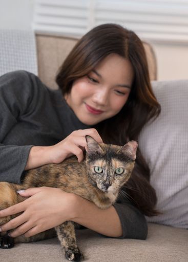 A woman lying on a couch, lovingly cuddling with her...