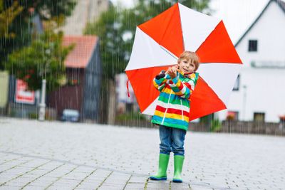 Smiling boy with yellow umbrella and colorful jacket...