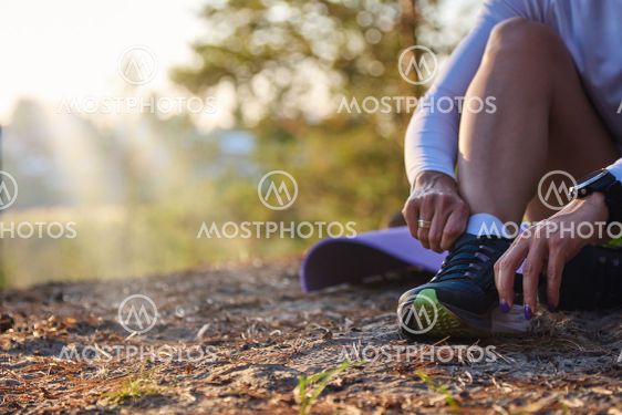 Woman ties her shoelaces on sneakers outdoors in the...