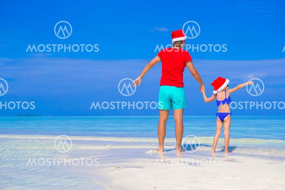 Happy father and his adorable daughter in Santa Hat at tropical beach