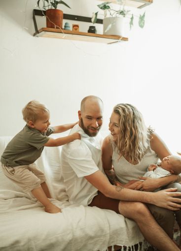 Parents, children and a playful family on the sofa in...
