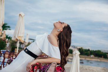 Beautiful brunette woman in white suit posing on the...