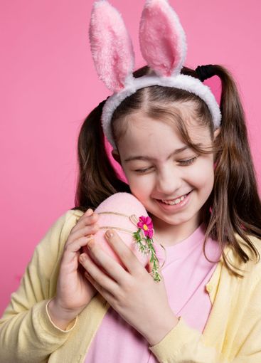 Cheerful toddler wearing bunny ears hugging a decorated...