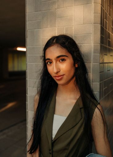 Portrait of teenage girl with long hair standing against...