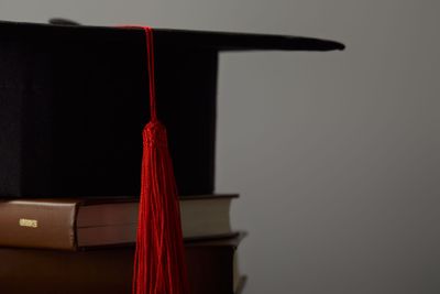Brown books and academic cap with red tassel isolated on...