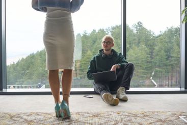 A blonde man sitting casually on the floor of a modern...