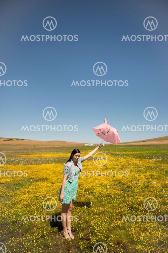 Beautiful adult smelling flowers on sunny field enjoying herself