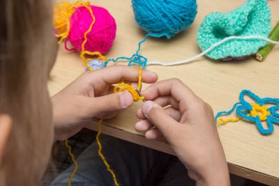 Hands of a child are embroidered with threads using a hook