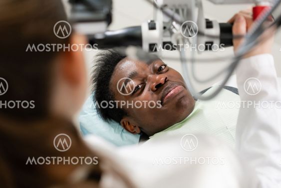 Young African American male patient at chair at dental...