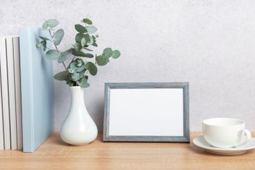 Eucalyptus branches, books, empty frame and coffee cup...