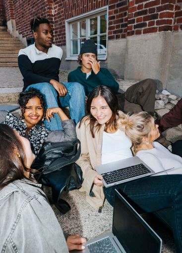 Group of multiracial male and female students sitting...