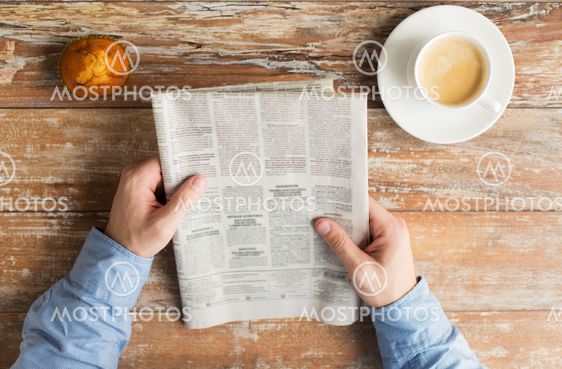 close up of male hands with newspaper and coffee