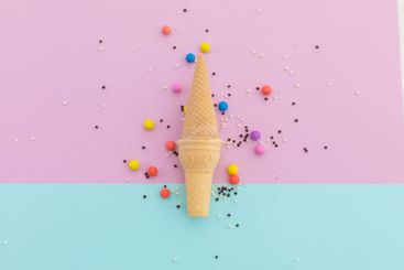 Two ice cream cones and scattered colourful sprinkle on...