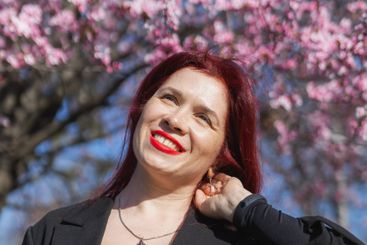 Red haired woman wearing stylish outfit near blossoming...