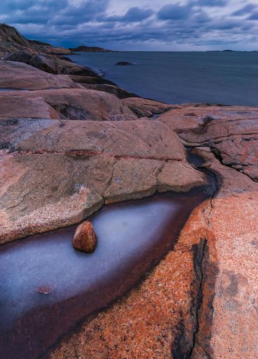 Coastal landscape featuring rocky shore and calm waters...
