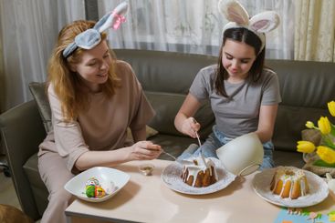 Mother and daughter decorating Easter cakes together.