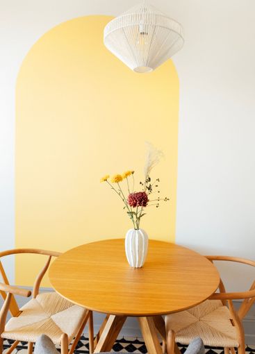 Close-up of a round wooden table with a vase of flowers....