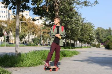 Handsome teenager standing with skateboard. Adolescent...